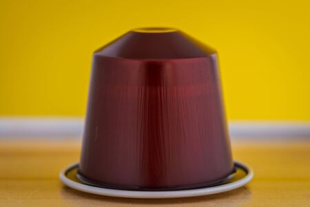 closeup lateral view of an aromatic, tasty espresso brown coffee capsule with yellow backgroundのeditorial素材