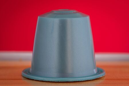 closeup lateral view of an aromatic, tasty espresso gray coffee capsule with red backgroundのeditorial素材