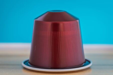 closeup lateral view of an aromatic, tasty espresso brown coffee capsule with light blue backgroundのeditorial素材