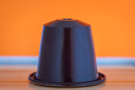 closeup lateral view of an aromatic, tasty espresso dark blue coffee capsule with orange backgroundのeditorial素材