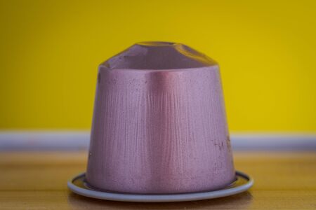 closeup lateral view of an aromatic, tasty espresso pink coffee capsule with yellow backgroundのeditorial素材