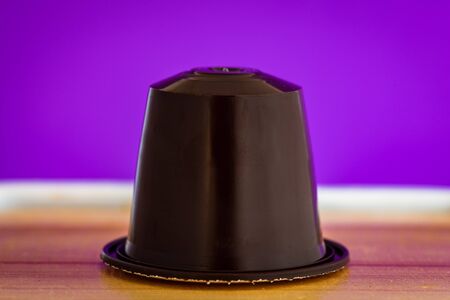 closeup lateral view of an aromatic, tasty espresso brown coffee capsule with purple backgroundのeditorial素材