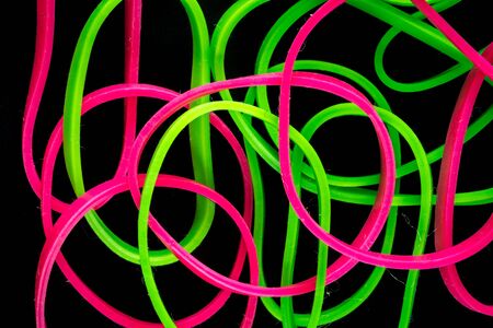 pile of colorful small rubber bands isolated on a black back ground randomly placedの写真素材