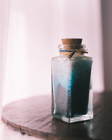 fancy bottle with blue bath salts for relaxing spa treatments with white background illuminated with...