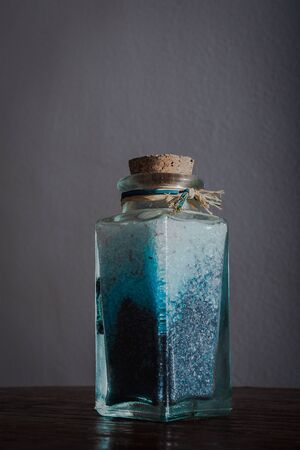 fancy bottle with blue bath salts for relaxing spa treatments with white background illuminated with natural lightの写真素材