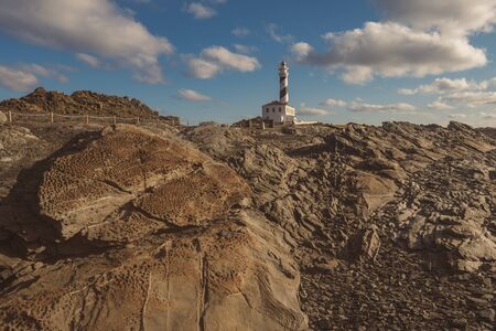 lighthouse at the morning in a sunny winter day with stony foreground in menorca, spainの写真素材