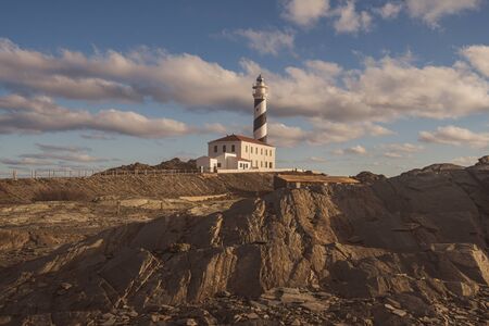 lighthouse at the morning in a sunny winter day with stony foreground in menorca, spainの写真素材