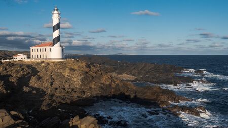 lighthouse at the morning in a sunny winter day with stony foreground in menorca, spainの写真素材