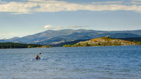 young athletic man on his kayak canoeing and enjoying alone the tranquility of Aguilar dam. Palencia, Spain.の写真素材