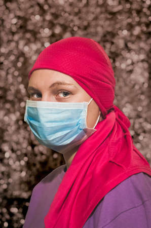 caucasian woman with breast cancer wearing disposable face mask and pink chemo hatの写真素材
