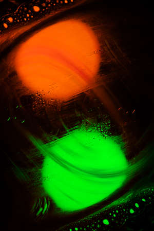 orange and green bulbs under moving water with dark backgroundの写真素材