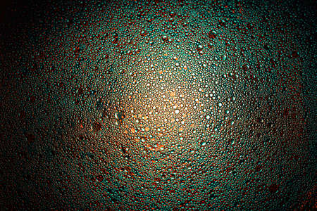 cyan, orange and teal oil droplets illuminated with colored bulb with dark background. Water and olive oil mixture.の写真素材