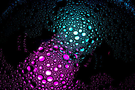 purple, magenta, teal and cyan droplets illuminated with colored bulb with dark background. Water and olive oil mixture.の写真素材