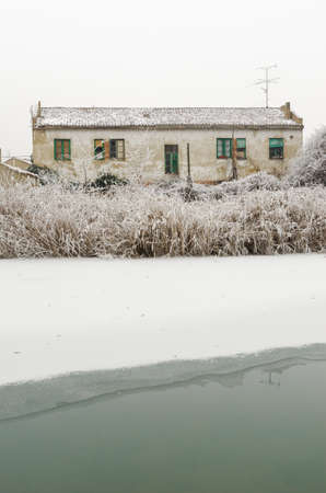 abandoned frozen dirty house after a winter storm in a cloudy dayの写真素材