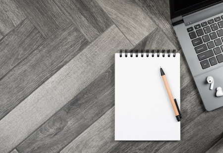 notepad spiral notebook pen AirPods wireless headphones keyboard computer on grey wooden backgroundの写真素材
