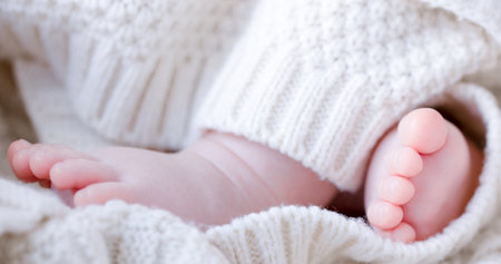 newborn baby feet in white wool blanket close up