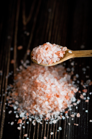 Pink himalayan salt in wooden spoon on brown wooden backgroundの写真素材