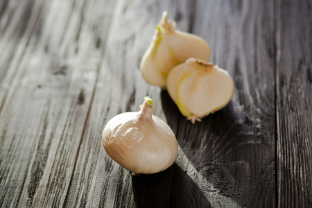 Close up whole natural white onion and sliced white onion on a brown wooden tableの写真素材