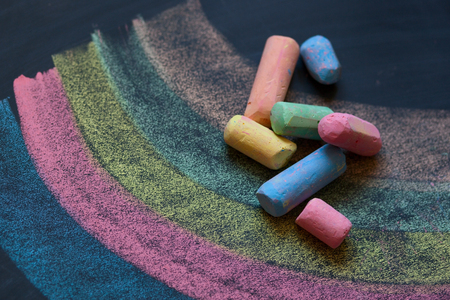 Colorful chalks on dark school board with painted multicolor rainbowの写真素材