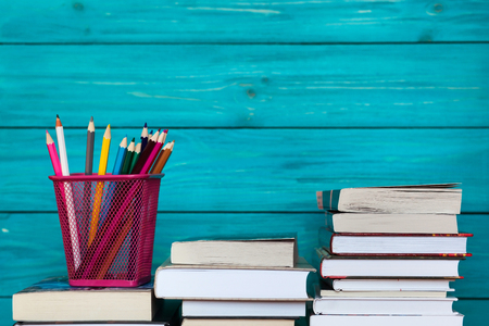 Stack of books and colorful pencils in front of turquoise wooden wall. Back to school ideaの写真素材