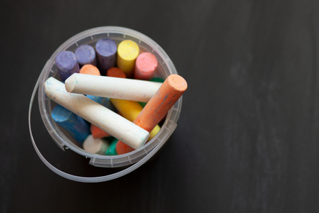 Black old empty chalkboard  with colorful pieces of chalk in plastic bucket.の写真素材