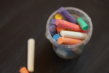 Black old empty chalkboard  with colorful pieces of chalk in plastic bucket.の写真素材