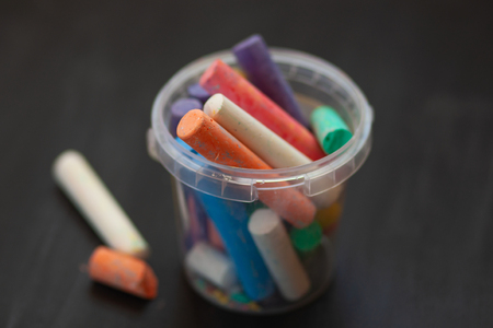 Black old empty chalkboard  with colorful pieces of chalk in plastic bucket.の写真素材