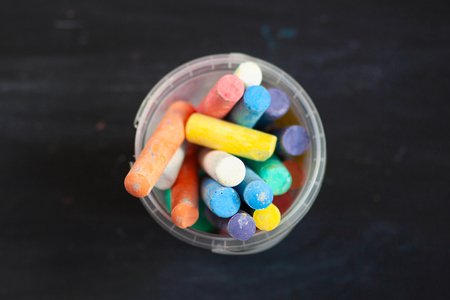 Black old empty chalkboard  with colorful pieces of chalk in plastic bucket.の写真素材