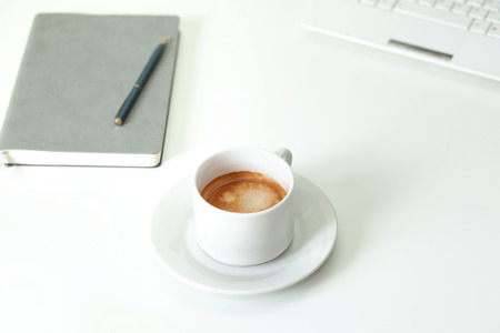 White workspace with coffee, notebook and computer. Office concept. Natural morning light.の写真素材