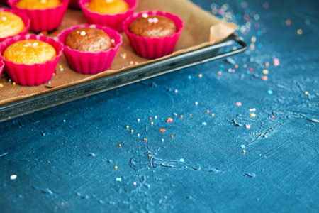 Delicious chocolate and vanilla cupcakes cooked in red tins on baking tray with baking paper on...