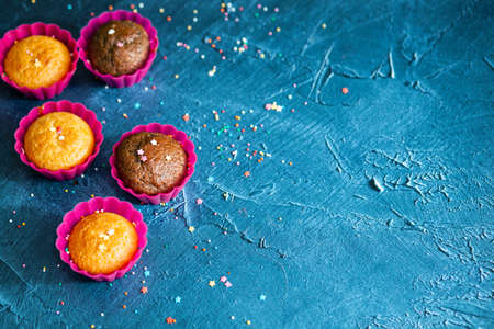 Delicious chocolate and vanilla cupcakes with sweet topping on textured concrete table, top view. Sweet pastriesの写真素材