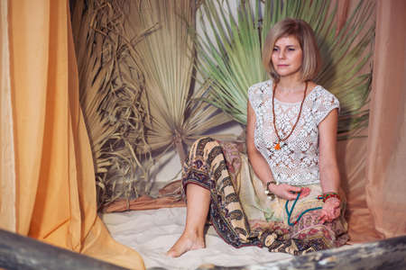 Calm woman meditating at meditate place in lotus position. The girl is dressed in ethnic clothes. natural materialsの写真素材