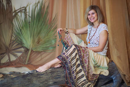 Calm woman meditating at meditate place in lotus position. The girl is dressed in ethnic clothes. natural materialsの写真素材