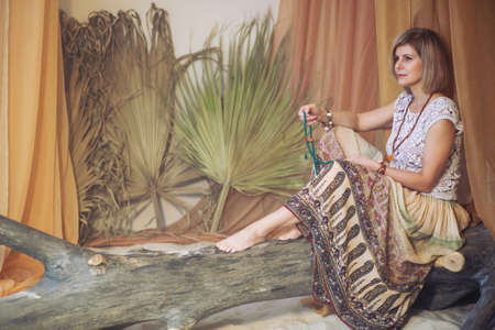 Calm woman meditating at meditate place in lotus position. The girl is dressed in ethnic clothes. natural materialsの写真素材
