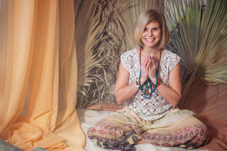 Calm woman meditating at meditate place in lotus position. The girl is dressed in ethnic clothes. natural materialsの写真素材