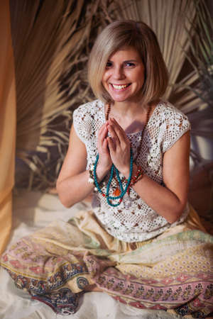 Calm woman meditating at meditate place in lotus position. The girl is dressed in ethnic clothes. natural materialsの写真素材