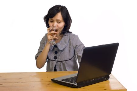 Beautiful asian business woman celebrating her success with wine in front of her computerの写真素材