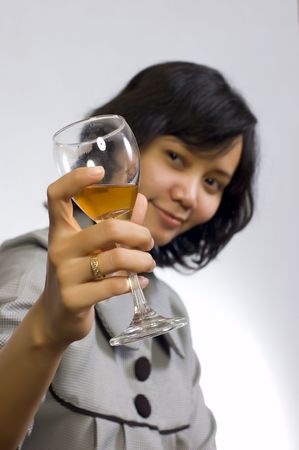 Young beautiful asian business woman celebrating her success with wine and sit on the tableの写真素材