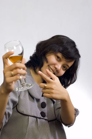 Young beautiful asian business woman celebrating her success with wine and sit on the tableの写真素材