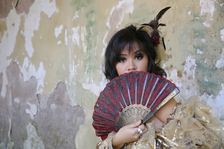 Chinese woman wearing victorian costume holding a fan, shoot at grunge buildingの写真素材