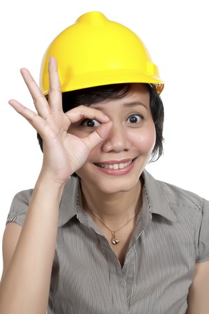 Female Engineer wearing yellow helmet gesturing ok isolated over white backgroundの写真素材
