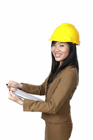 Female Engineer wearing yellow helmet holding paperboard isolated over white backgroundの写真素材