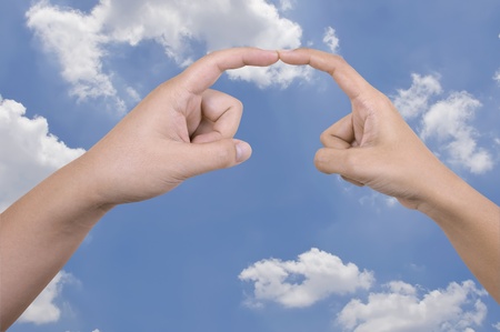 Man's and woman's hand touch againts the blue skyの写真素材