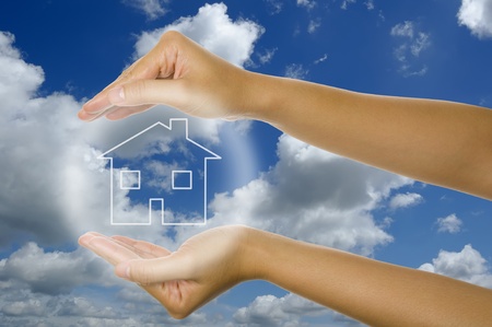 Woman hand and glowing house icon with blu sky backgroundの写真素材