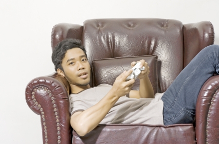 Young male playing video game on the couch on living roomの写真素材