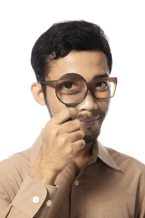 Funny young man looking through magnifying glass, isolated on whiteの写真素材