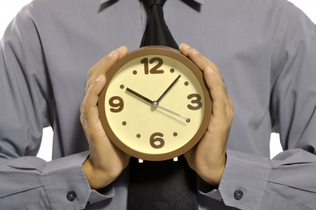 Businessman holding clock in his hand isolated over white backgroundの写真素材