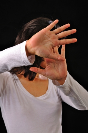 Portrait of asian woman cover her face isolated over black backgroundの写真素材