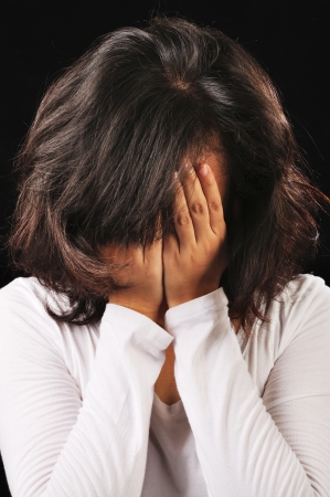 Portrait of asian woman cover her face isolated over black backgroundの写真素材