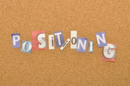 Positioning word made from newspaper letter shot over pinboard backgroundの写真素材